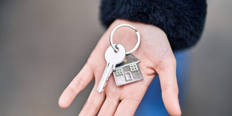 Young woman holding key of new home at street